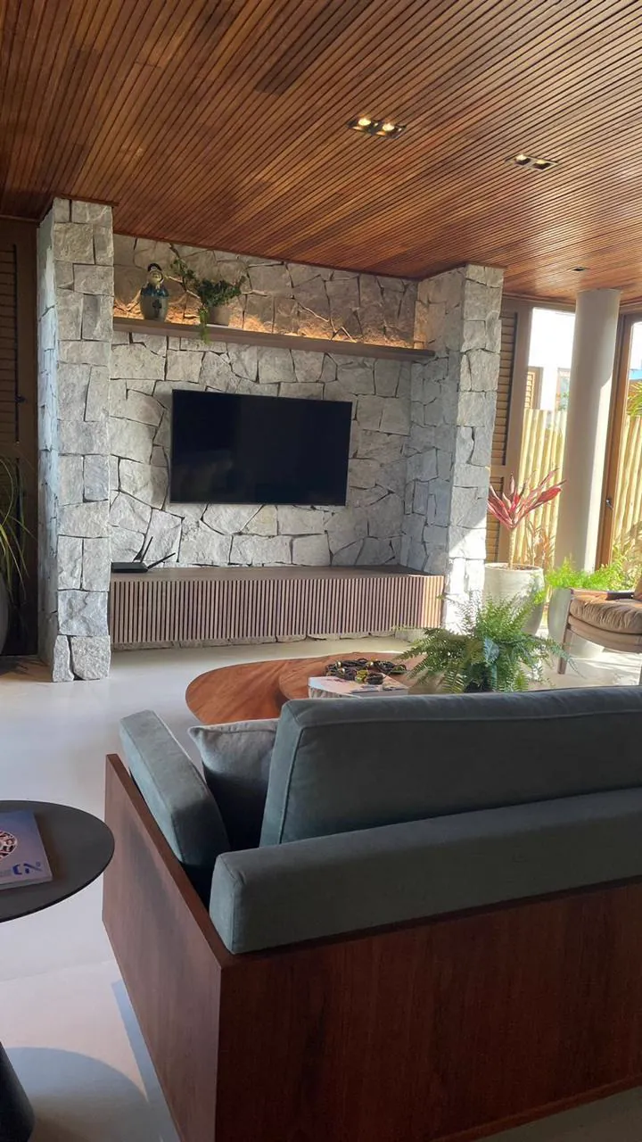 Sala de estar com painel de pedra e TV