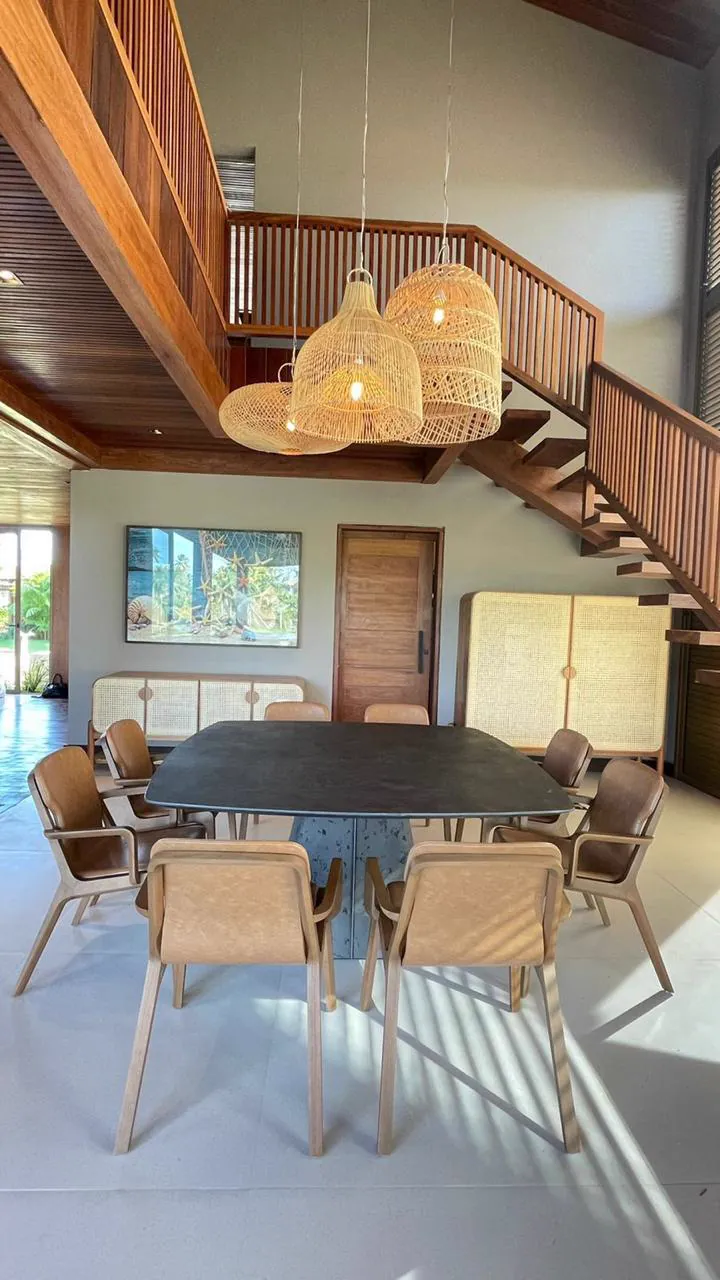 Sala de jantar com mesa para dez e escada em madeira