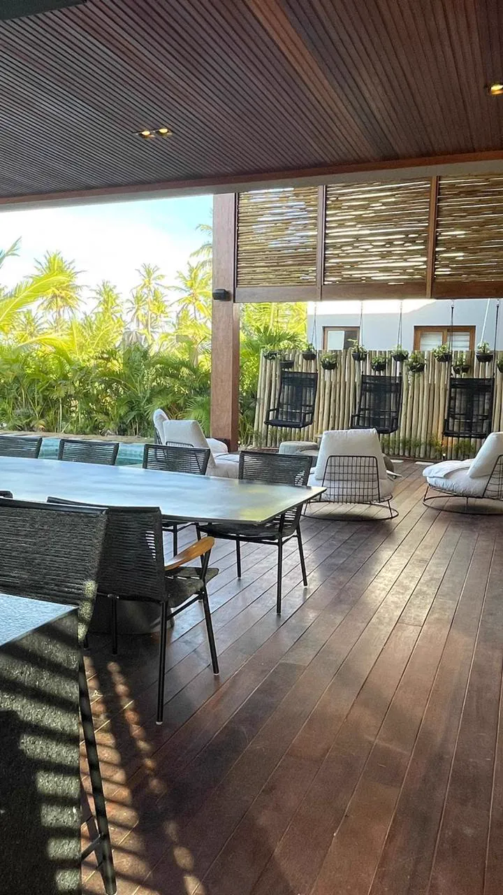 Varanda com mesa de jantar e cadeiras suspensas, de frente para o verde