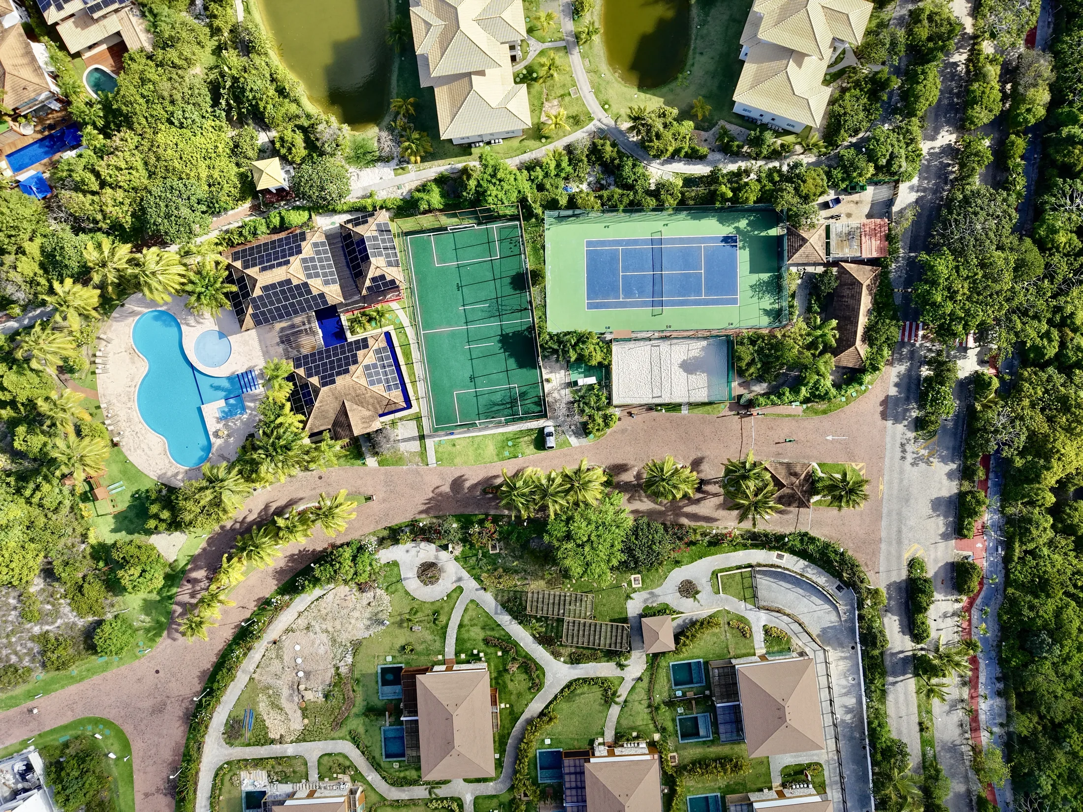 Vista aérea do clube do condomínio, com piscina, quadras e jardins