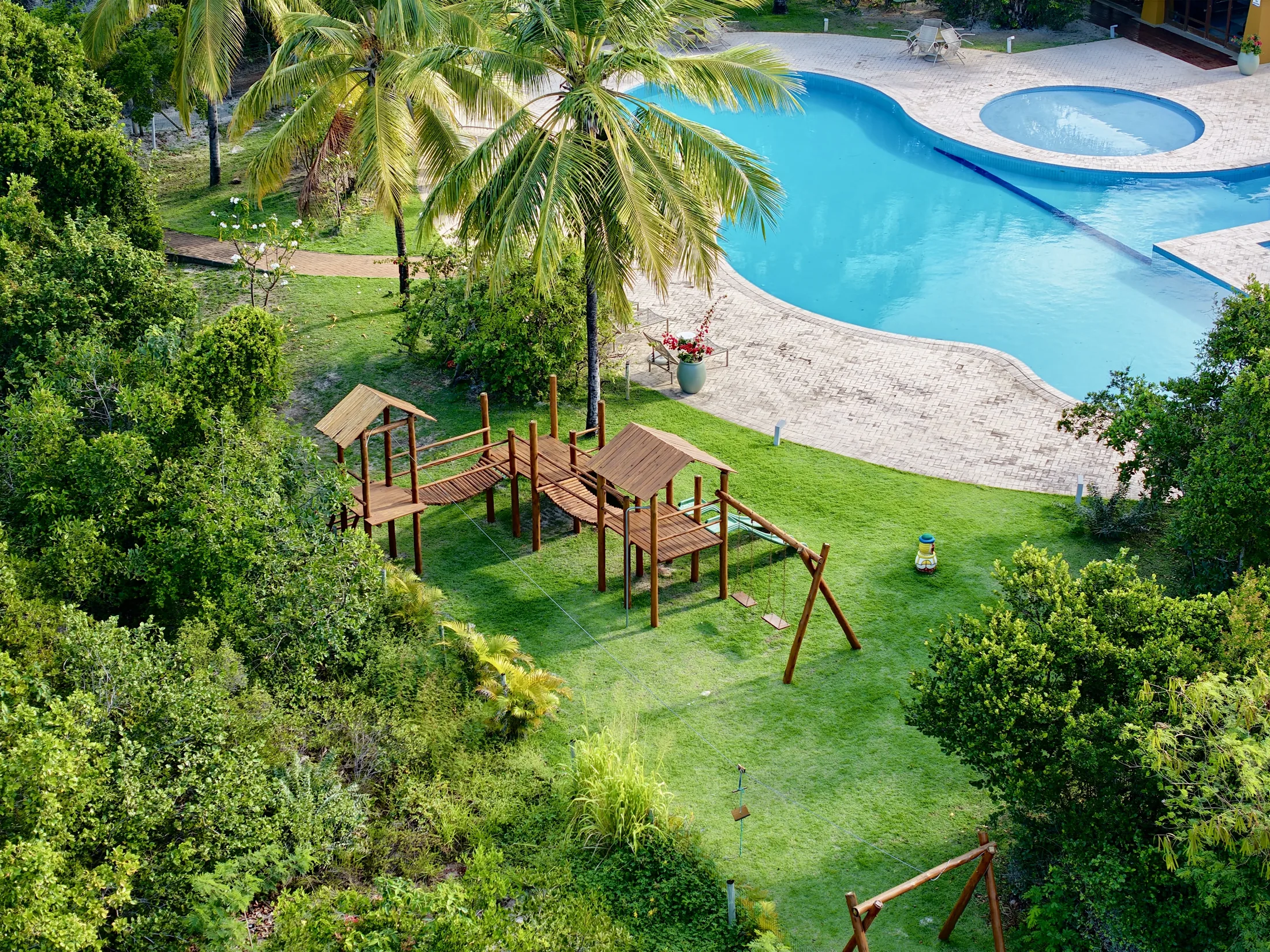 Piscina do clube com parque infantil e coqueiros, vista de cima