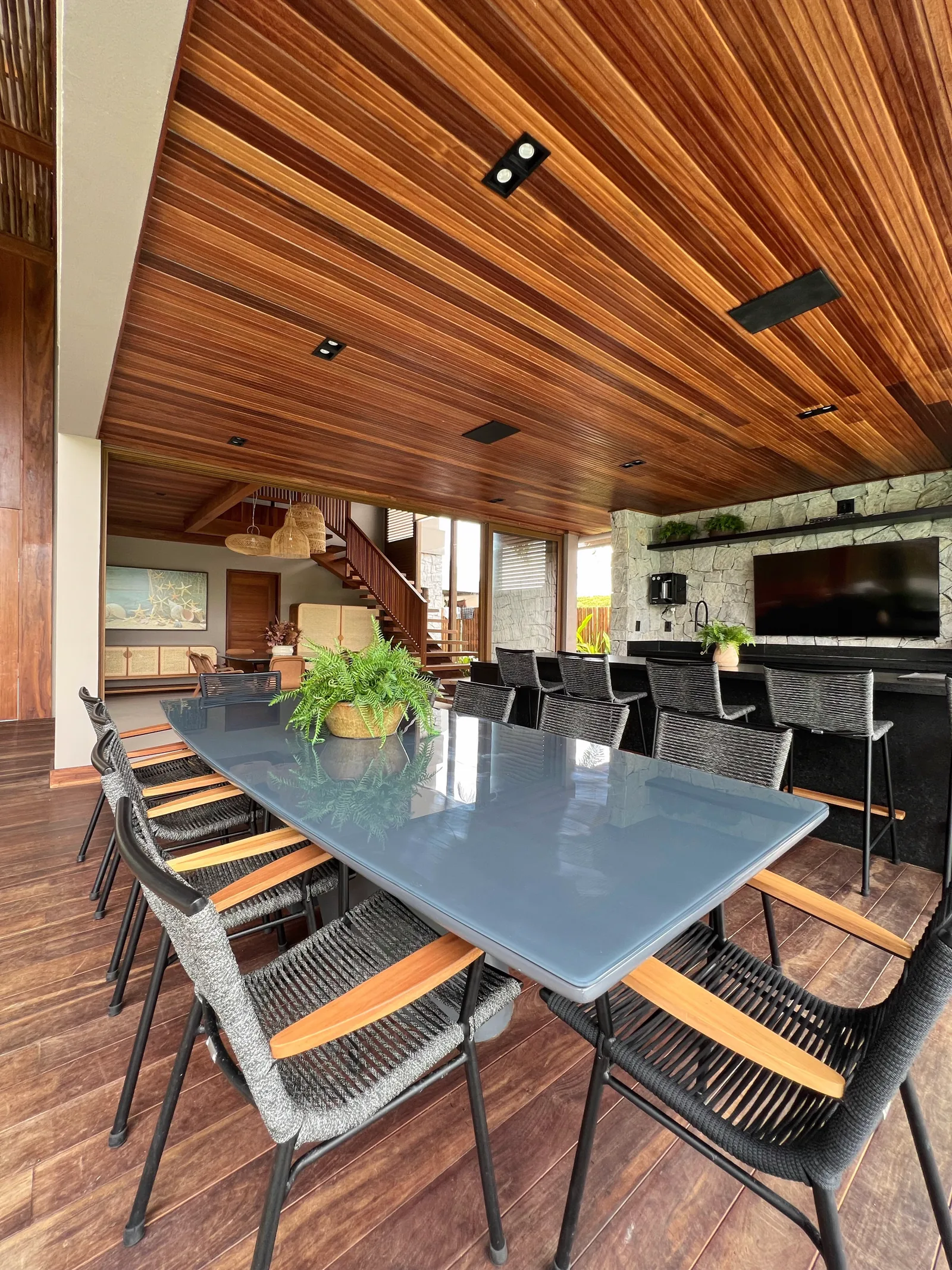 Espaço gourmet com mesa ampla, bar e painel de pedra