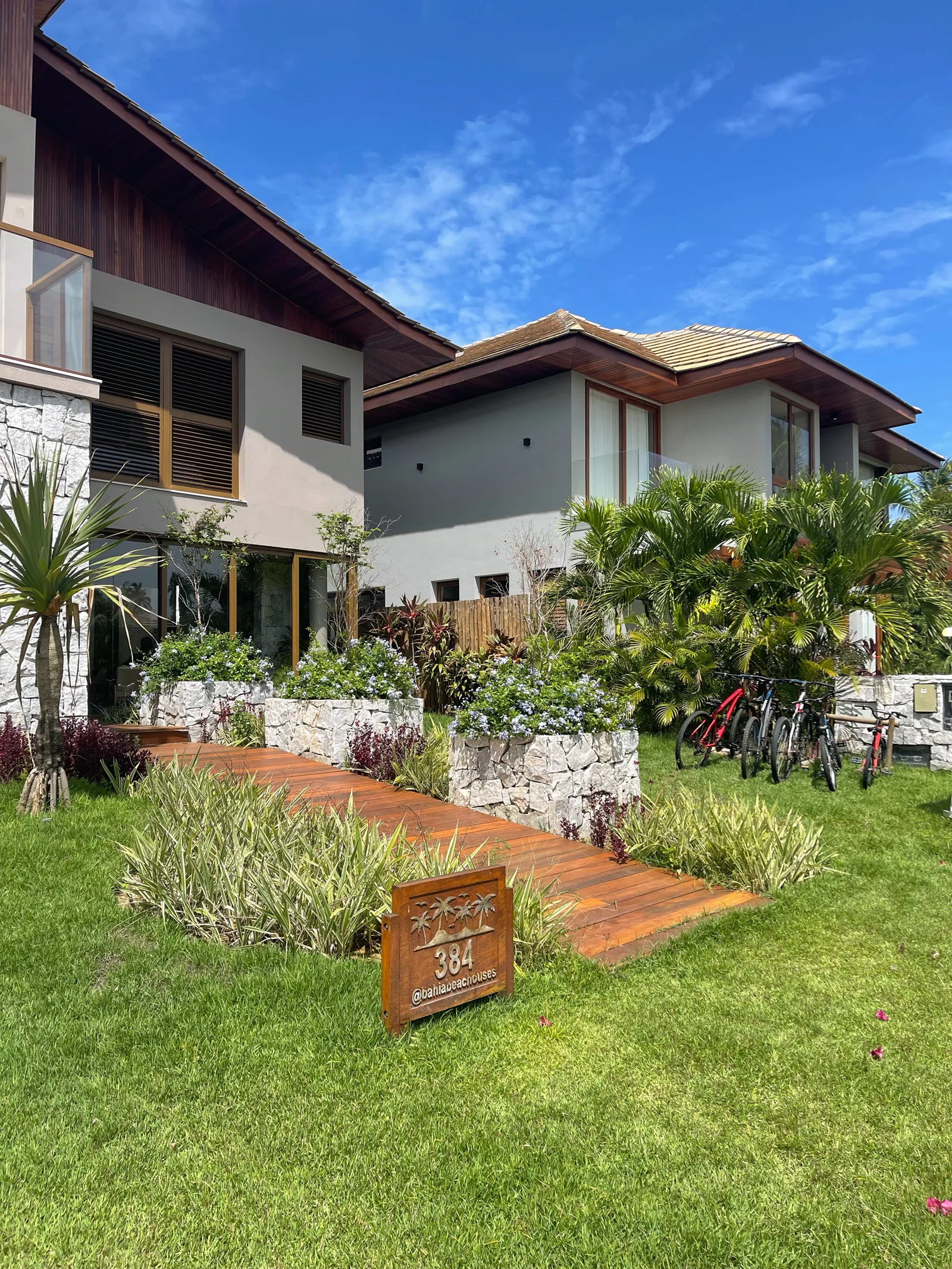 Fachada da Casa 384 e jardim, com o letreiro da casa e bicicletas
