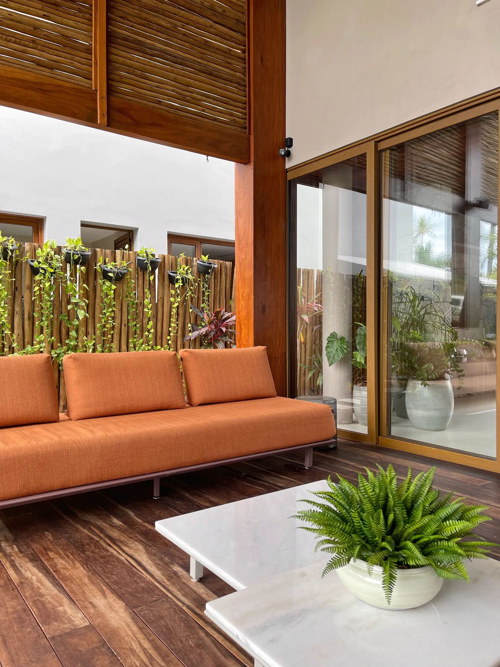 Terraço com sofá e trepadeiras no painel de madeira