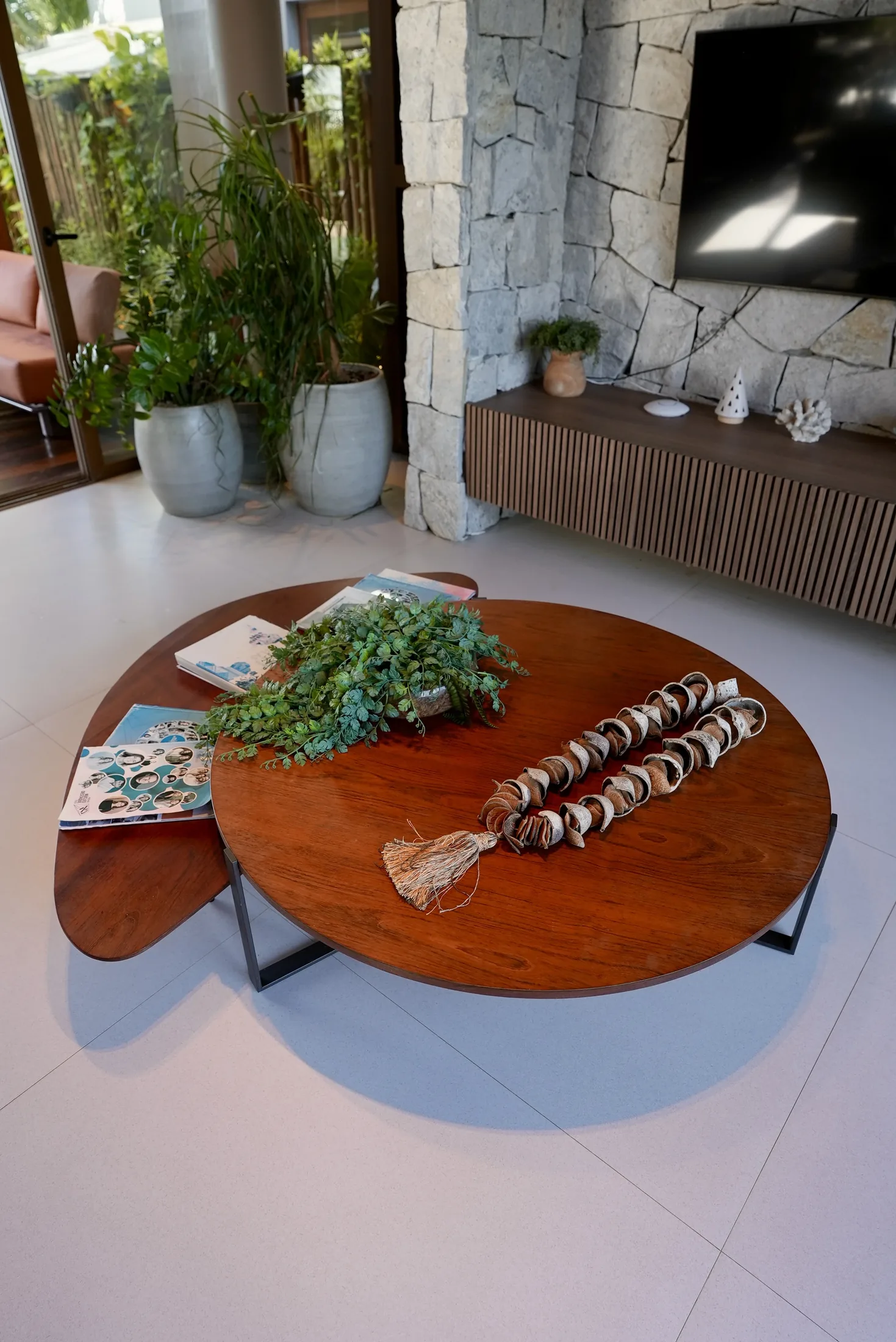 Detalhe da mesa de centro redonda de madeira, com o living ao fundo