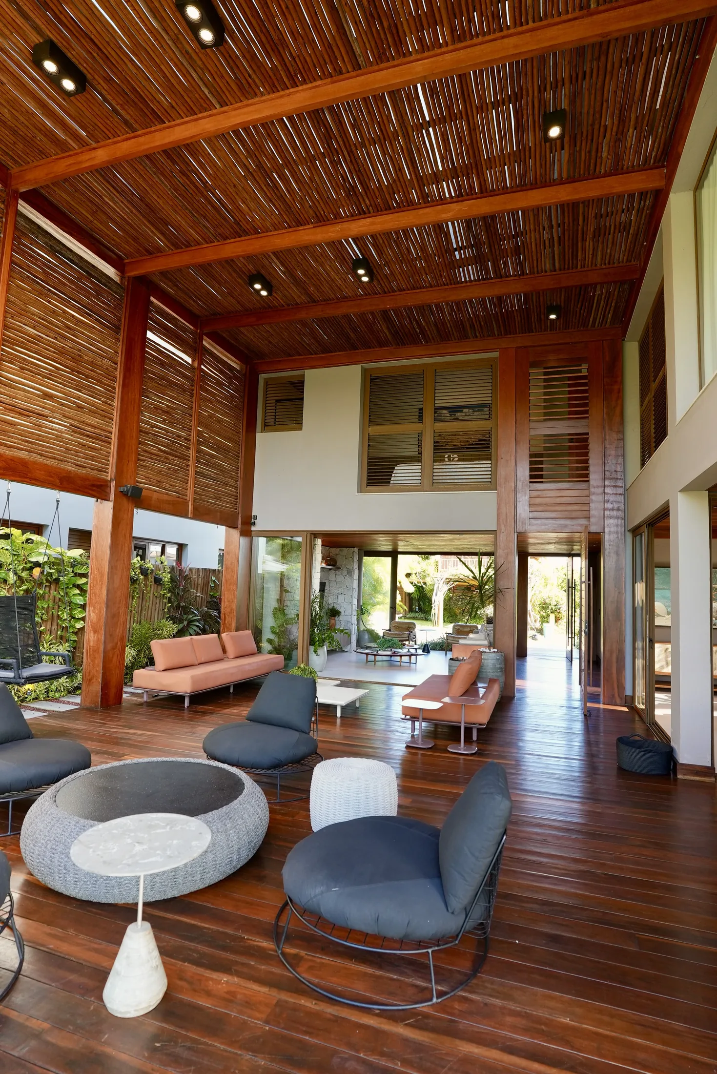 Lounge do terraço com pufe redondo e poltronas, aberto para o jardim