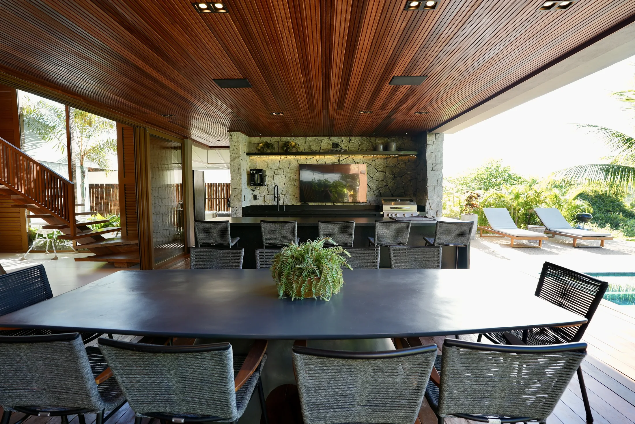 Espaço gourmet com mesa de jantar longa aberta para a piscina