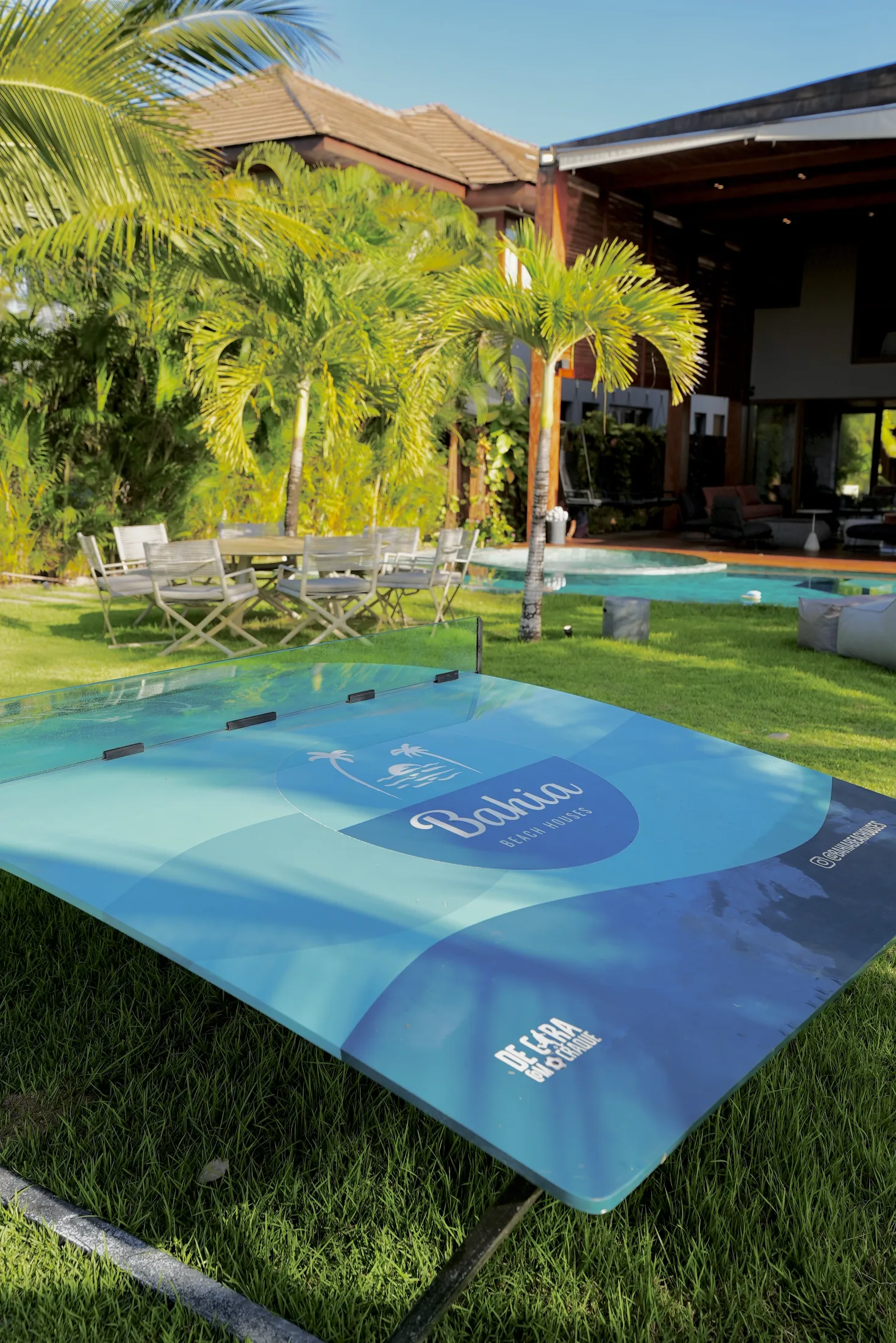 Mesa de ping-pong no gramado, com a fachada da casa ao fundo