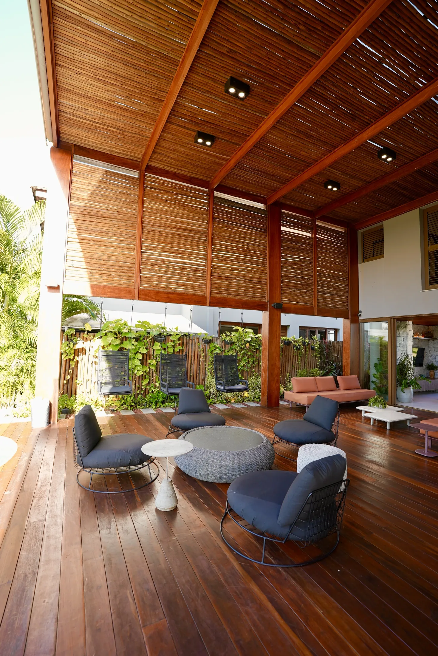 Terraço com poltronas e o painel de madeira com trepadeiras