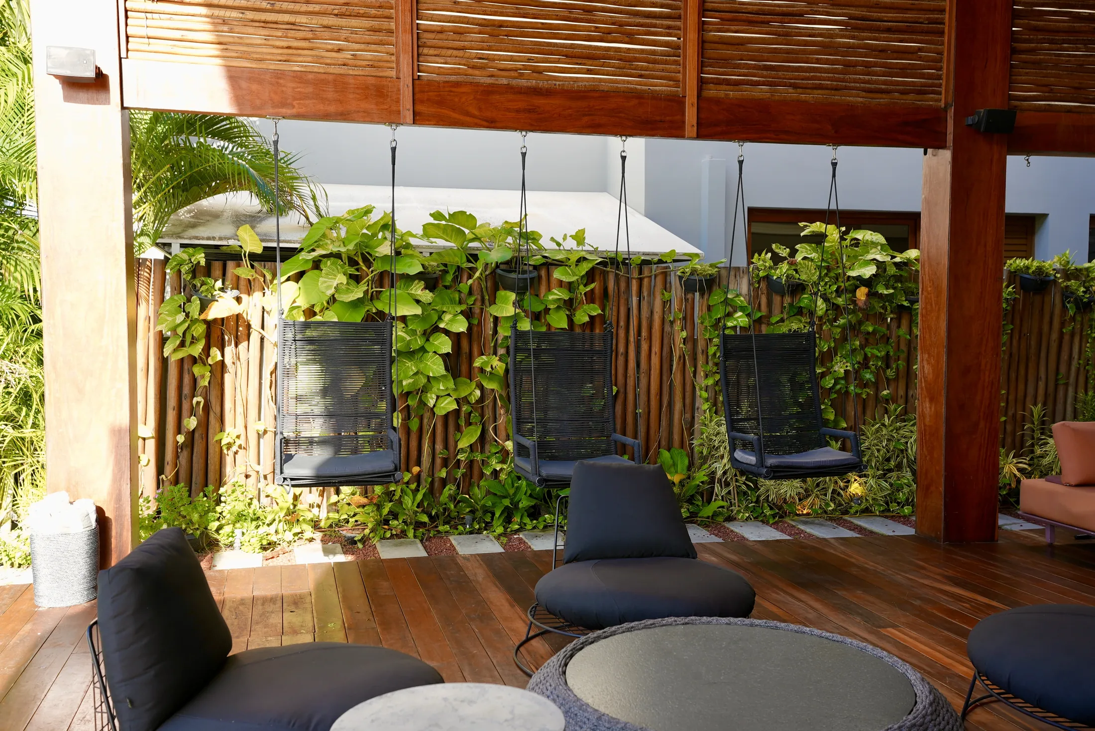 Parede verde de trepadeiras e poltronas no terraço coberto